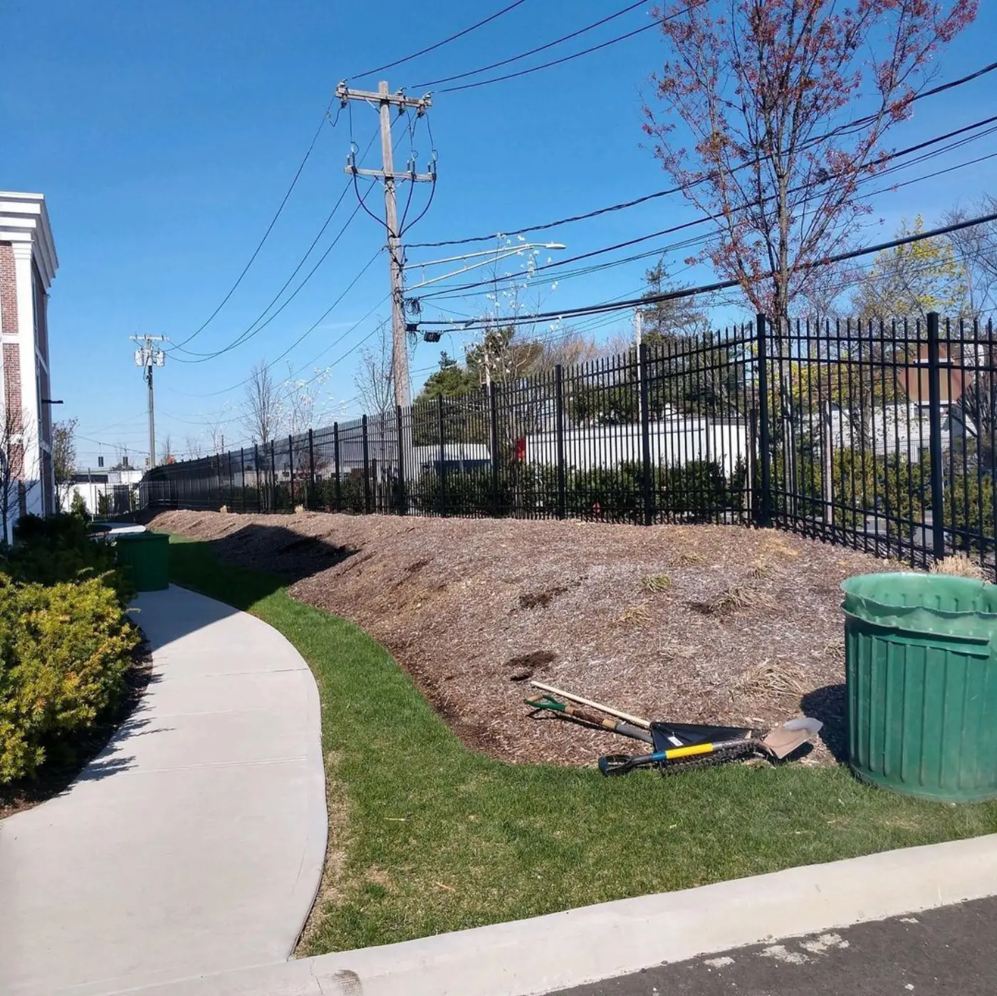 Overgrown slope of matted old mulch and weeds along a commercial walkway